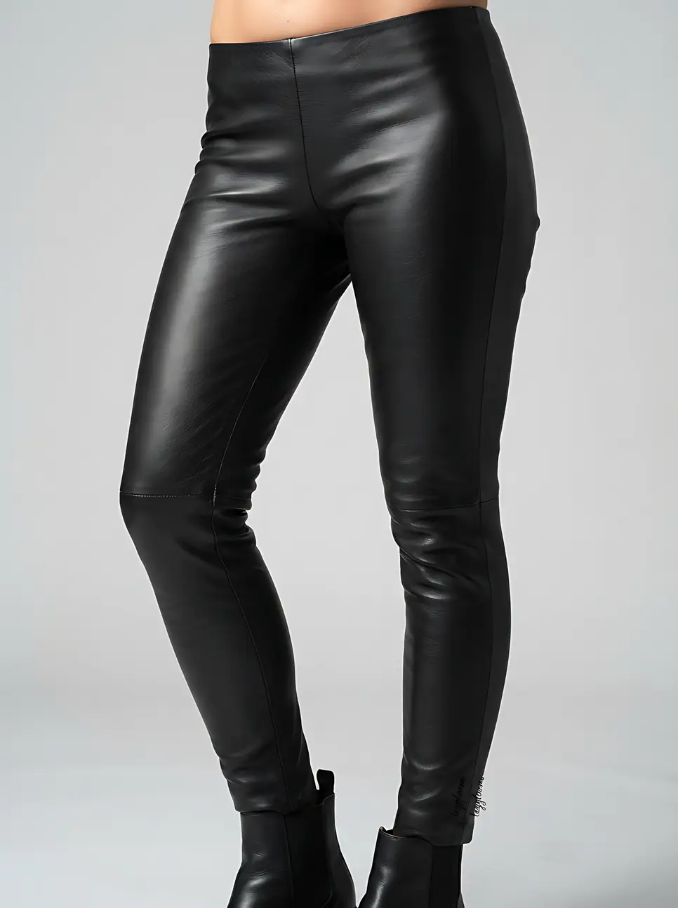 Studio shot of legs in black leather leggings and boots.
